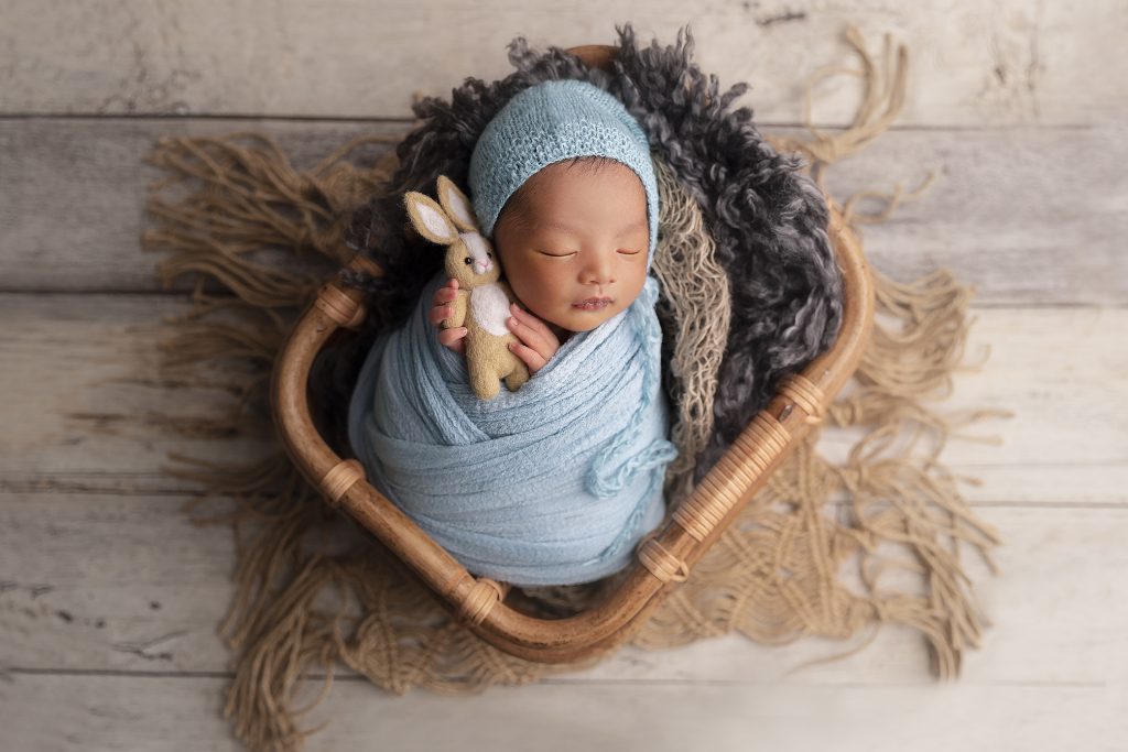 Cute baby was posed in a basket during his newborn photography session at our Sydney studio.