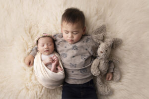 A toddler was holding his newborn baby sister during their photo session at Capture The Moment By Ana, Sydney.