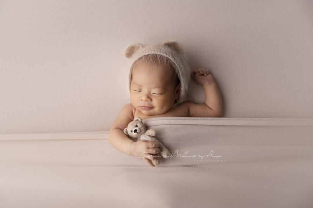 A baby girl is holding her little bear posed for her newborn photography session in Sydney.